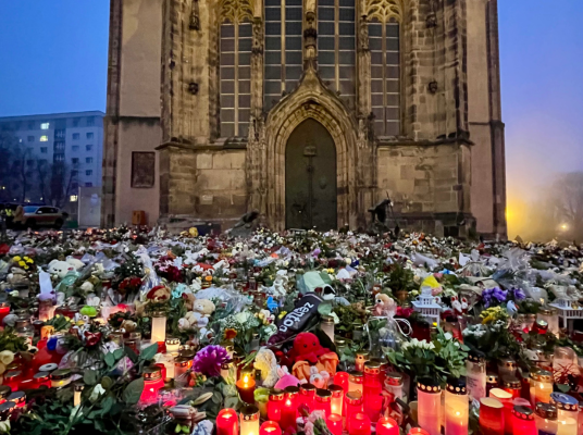 Blumen- und Kerzenmeer vor dem Westportal einer Kirche.